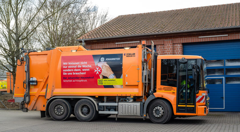 Ein Müllwagen, der beklebt ist mit: "Wir kommen nicht nur einmal die Woche, sondern dann, wenn Sie uns brauchen! Der Johanniter-Hausnotruf"