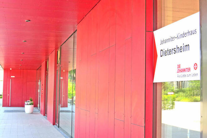 Eine Rote Hauswand mit großen Fenstern des Johanniter Kinderhauses in Dietersheim.