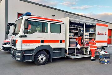 Johanniter-Rettungsfahrzeug mit offener Seite, ein Helfer in orangefarbener Einsatzkleidung arbeitet konzentriert daneben.