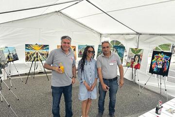 Drei Mitarbeitende der Johanniter stehen in dem Zelt, in dem die Ausstellung "Gestrandet in Kiel" zu sehen ist.