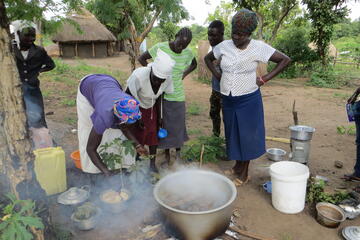 Kochende Frauen mit dampfendem Topf