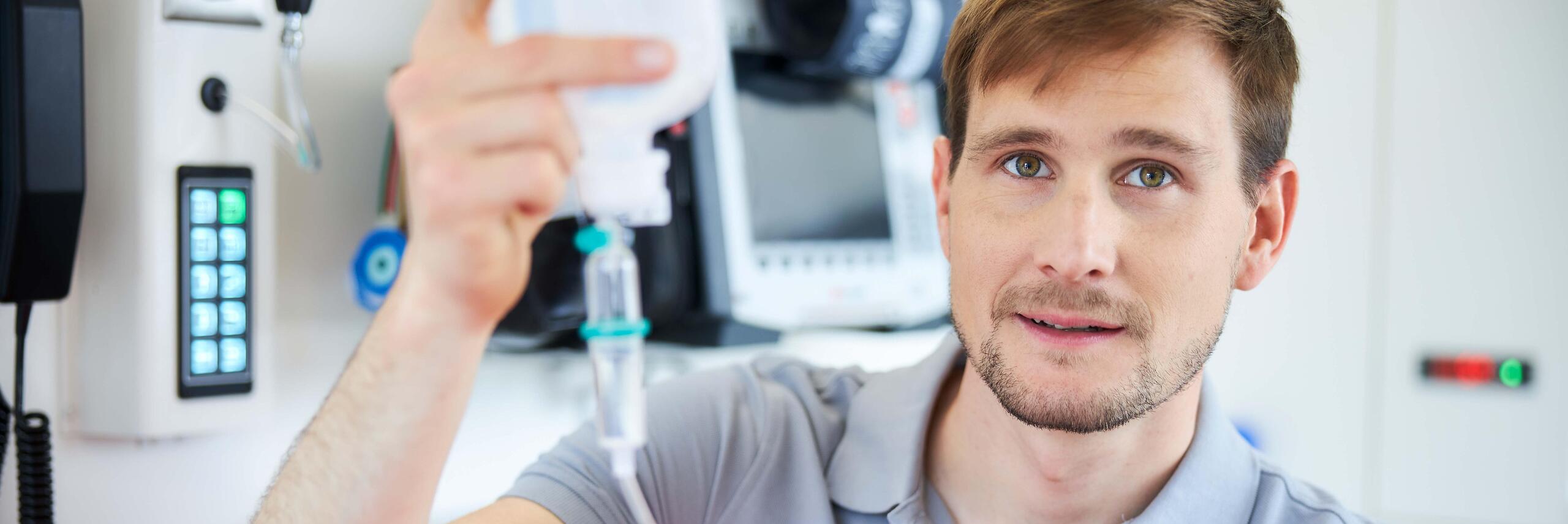 Notfallsanitäter im Rettungswagen mit Infusion in der Hand