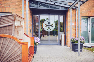 Glastür-Eingang mit Johanniter Logo, links vor dem Eingang steht ein Strandkorb