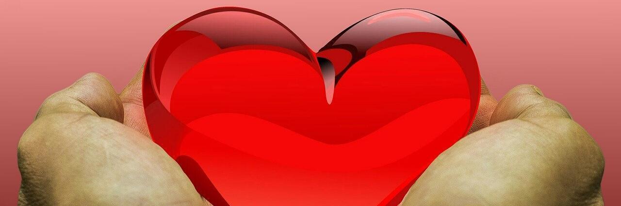 Hände umfangen ein rotes Herz
