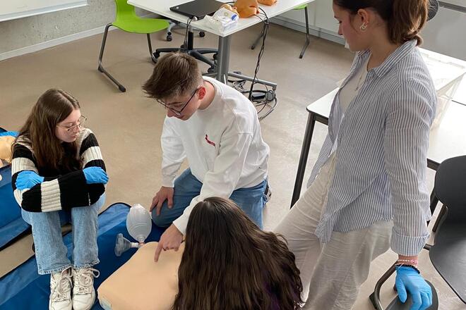 Ein Jugendlicher erklärt anderen Schülern Erste Hilfe.