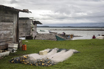 Ein Fischernetz liegt neben einem Haus, im Hintergrund ist Wasser zu sehen