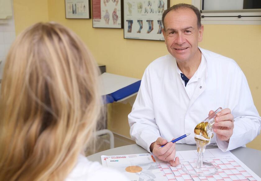 Dr. Paul bei einer Patientenbesprechung über ein Kniegelenk 