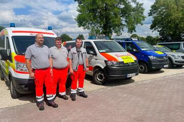 Portraitfoto von mehreren Einsatzkräften vor Einsatzfahrzeugen 
