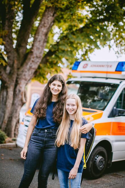 Zwei Mädchen aus der Johanniter-Jugend vor einem RTW