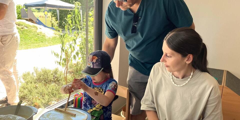 Ein Varer mit Kind und eine Erzieherin beim Waffeln backen