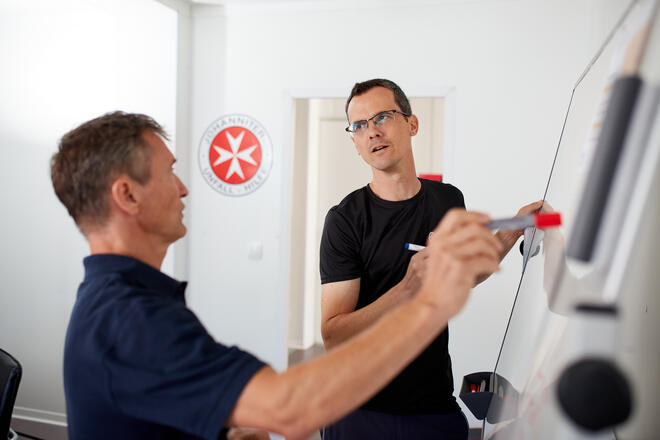 Zwei Mitarbeiter der Johanniter-Fluthilfe arbeiten an einem Flipchart