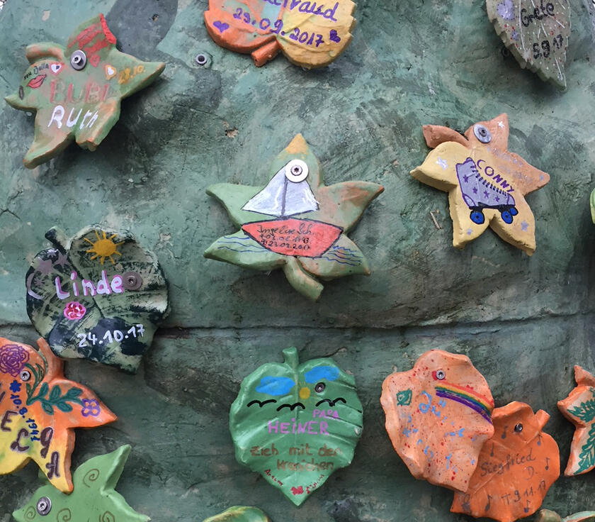 Bunte Blätter aus Ton werden zum Abschied der Gäste an den Baum gehängt