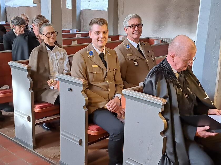 Mehrere Johanniter in Dienstkleidung sitzen in den Kirchenbänken.