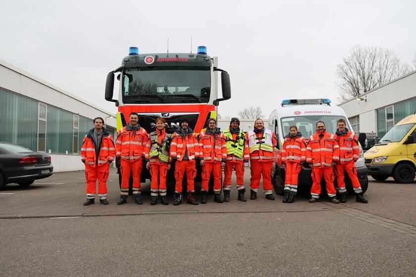 Sanitäterinnen und Sanitäter stehen in Einsatzkleidung vor zwei Einsatzfahrzeugen der Johanniter Heilbronn und schauen für ein Gruppenbild in die Kamera.
