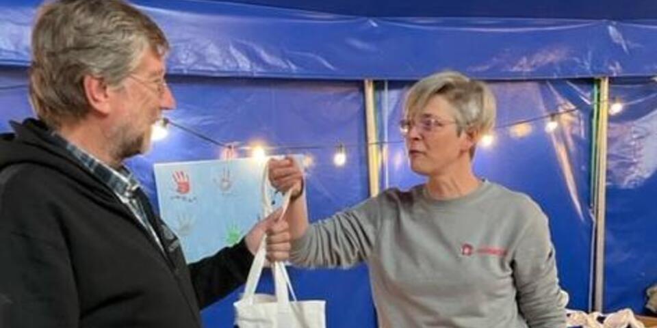 Eine Mitarbeiterin übergibt eine Tasche