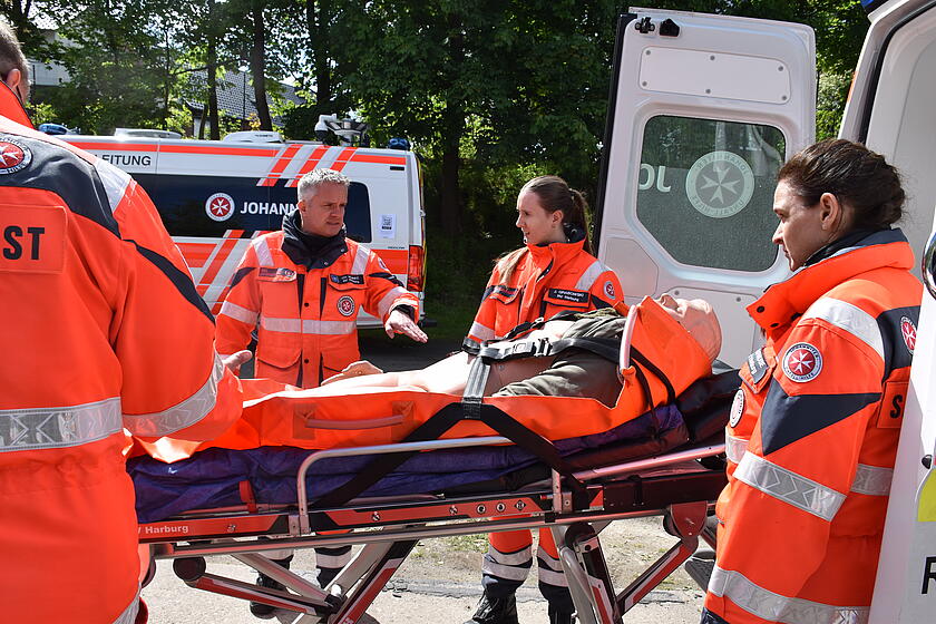 Johanniter‑Team versorgt eine Übungspuppe auf Trage neben einem Rettungswagen