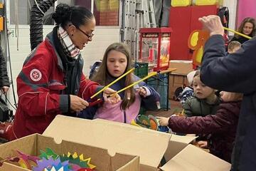 Eine Mitarbeiterin gibt einem Kind eine Laterne?