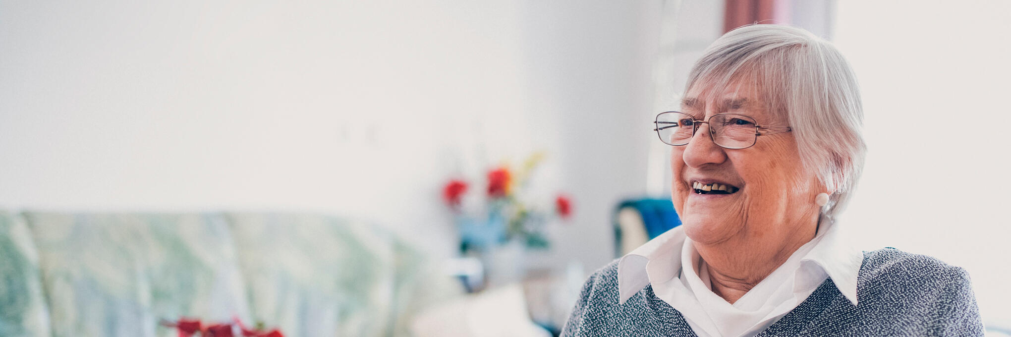 Bewohnerin mit Strickzeug vor einem Wohnzimmertisch