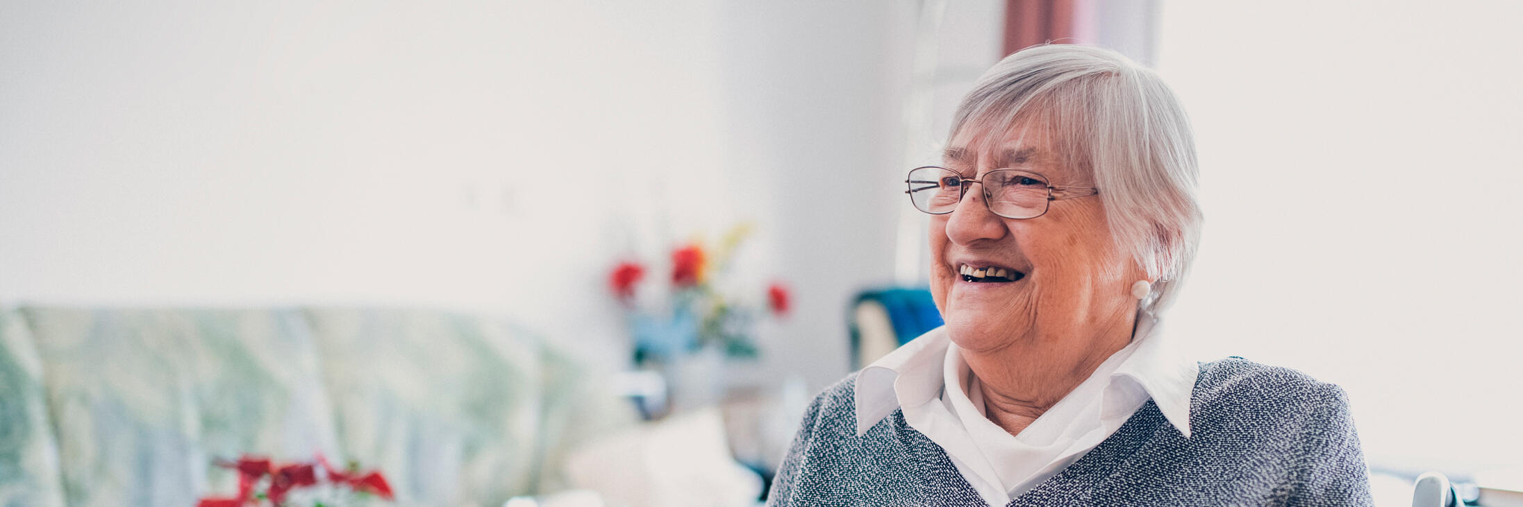 Bewohnerin mit Strickzeug vor einem Wohnzimmertisch