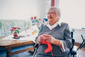 Bewohnerin mit Strickzeug vor einem Wohnzimmertisch