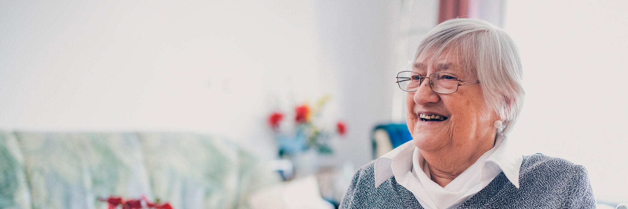 Bewohnerin mit Strickzeug vor einem Wohnzimmertisch