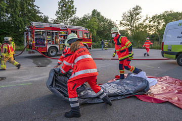 Eine Ehrenamtliche rollt den Teil eines Zeltes auf.