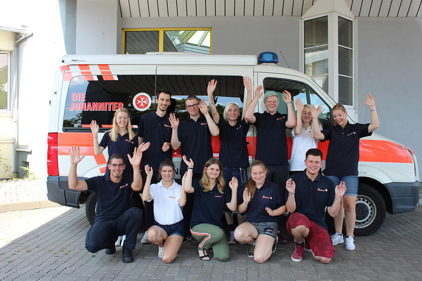Bunderfreiwilligendienstler vor einem Johanniter-Einsatzwagen.