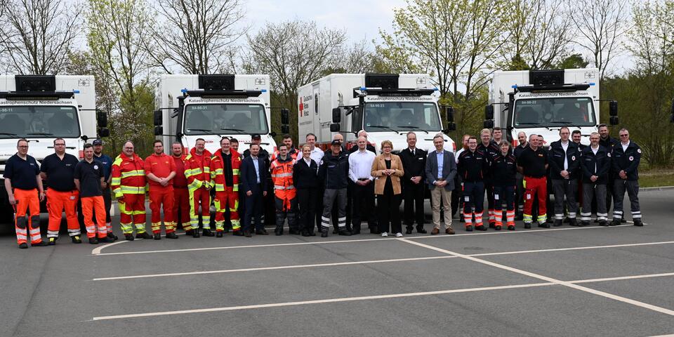 Menschen in Einsatzkleidung vor geländegängigen Krankentransportwagen