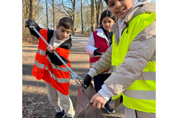 Auch Kinder sind fleißig mit dabei, sie heben den Müll auf und tun ihn in Säcke.