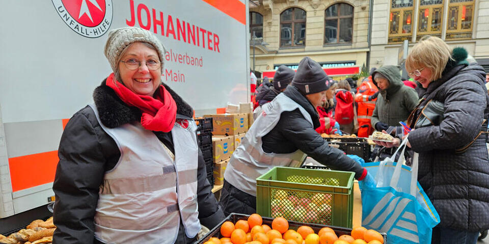 Johanniterinnen teilen frische Orangen bei der Johanniter-Suppenküche aus.