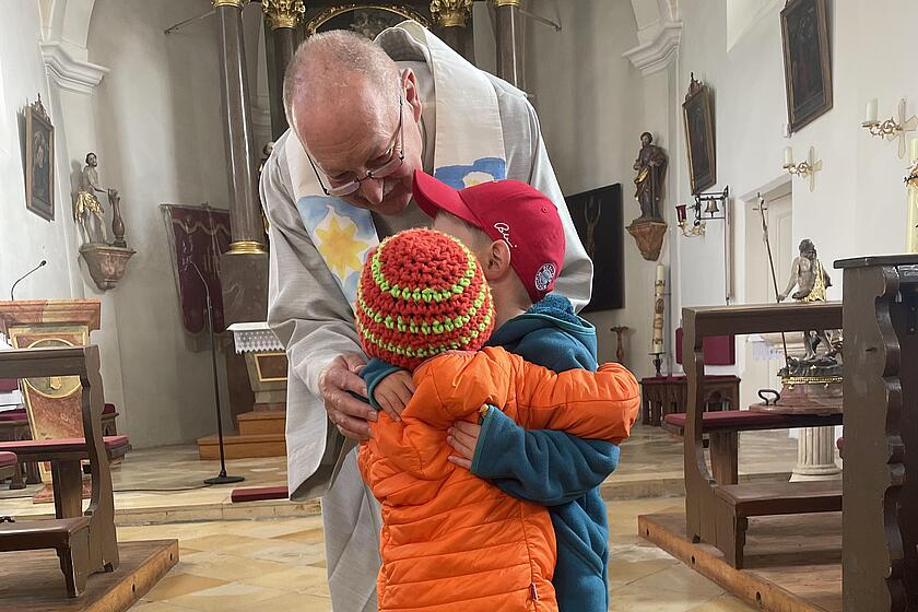 Kinder umarmen sich in der Kirche.