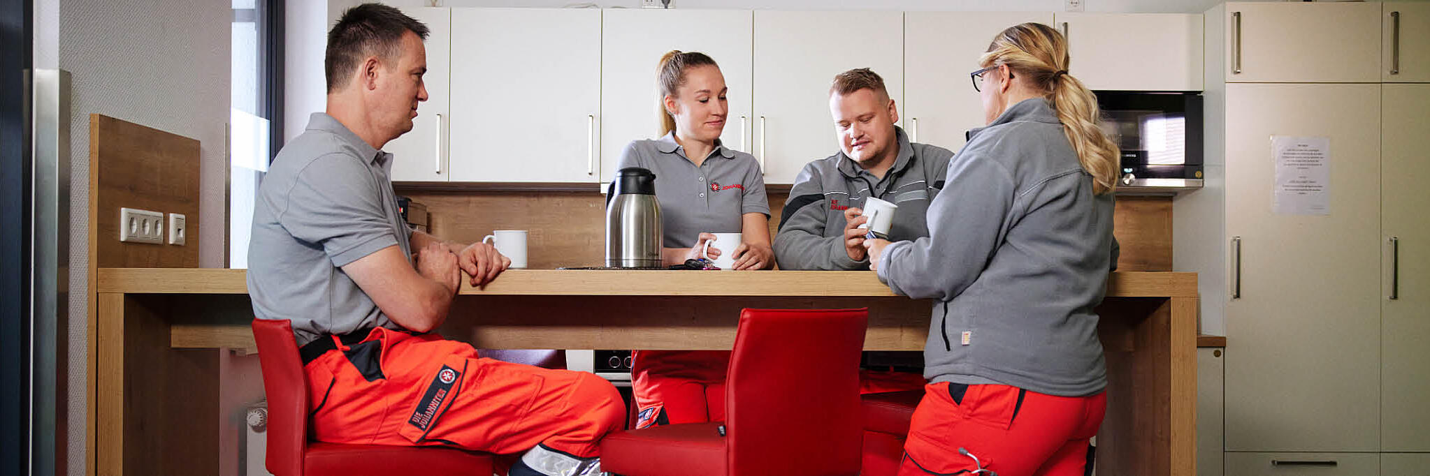 Mehrere Rettungskräfte sitzen zusammen an einem Tisch im Pausenraum