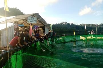 Männer stehen um einen der schwimmenden Käfige herum