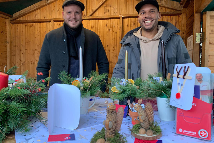 Zwei Mitarbeiter am Johanniterstand auf dem Weihnachtsmarkt