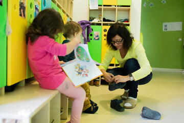 Erzieherin zieht einem Kind Schuhe an