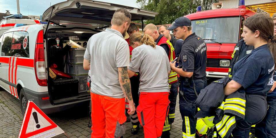 Einsatzkräfte an einem Einsatzwagen