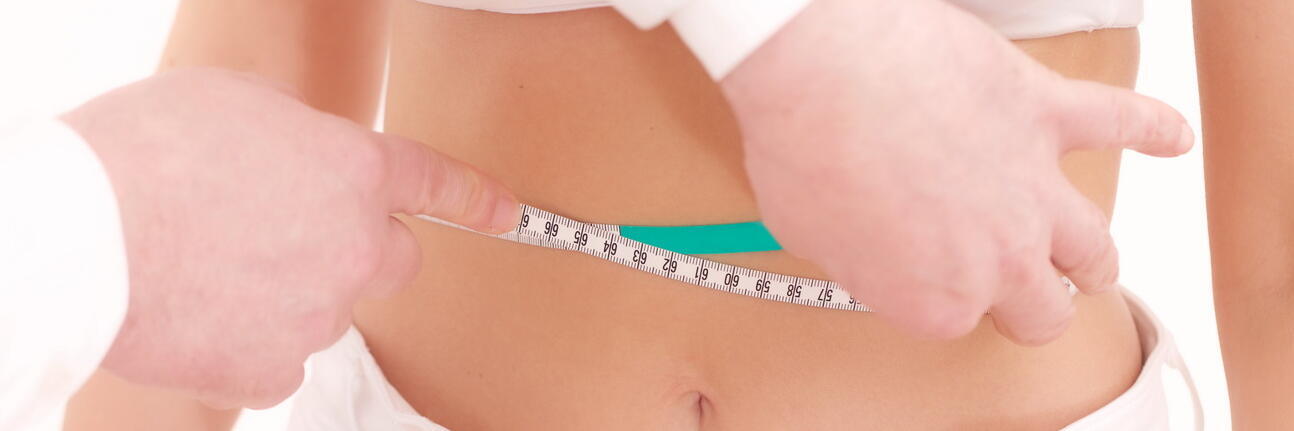 Arzt, der den Bauchumfang einer Frau mit Maßband misst