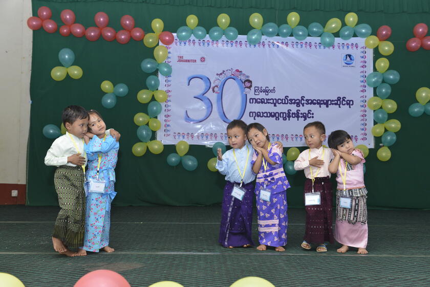 Kinder spielen vor einem Banner der Johanniter