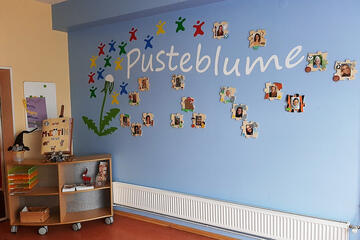 An einer Wand sind die Bilder der Teammitglieder des Johanniter-Haus Pusteblume angebracht.