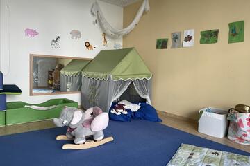 Ein Raum mit krippengerechten Spielsachen und einer Elefantenwippe.