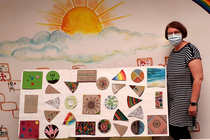 Treffpunktmitarbeiterin zeigt die Ergebnisse der Mal- und Bastelaktion