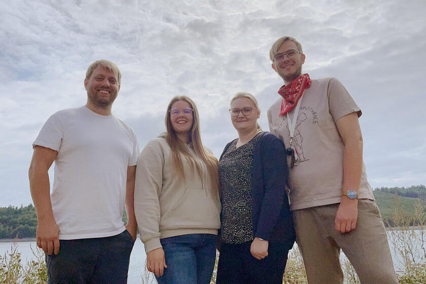 Vier Johanniter stehen nebeneinander vor einem See und gucken motiviert in die Kamera.