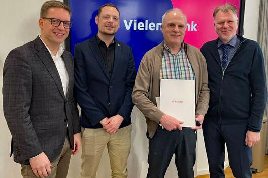 Vier Männer. Einer hält eine Urkunde in der Hand.