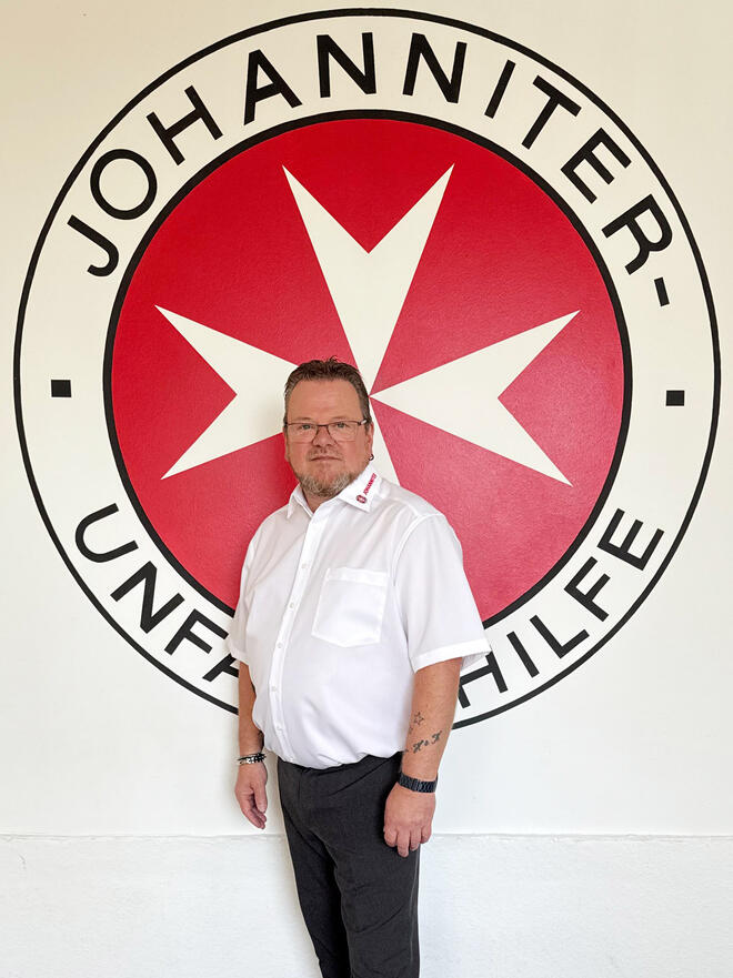 Der Fahrdienstleiter und Dienststellenleiter Preetz, Herbert Bär, steht vor dem Johanniter-Logo