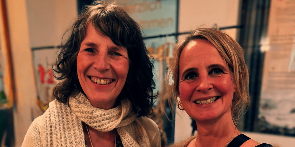 Zwei lächelnde Frauen als Portraitaufnahme bei einer Marktveranstaltung, freundliche Atmosphäre