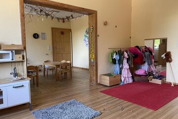 Ein Raum mit Spielküche sowie einer Verkleidungsecke mit vielen Kostümen und Requisiten.