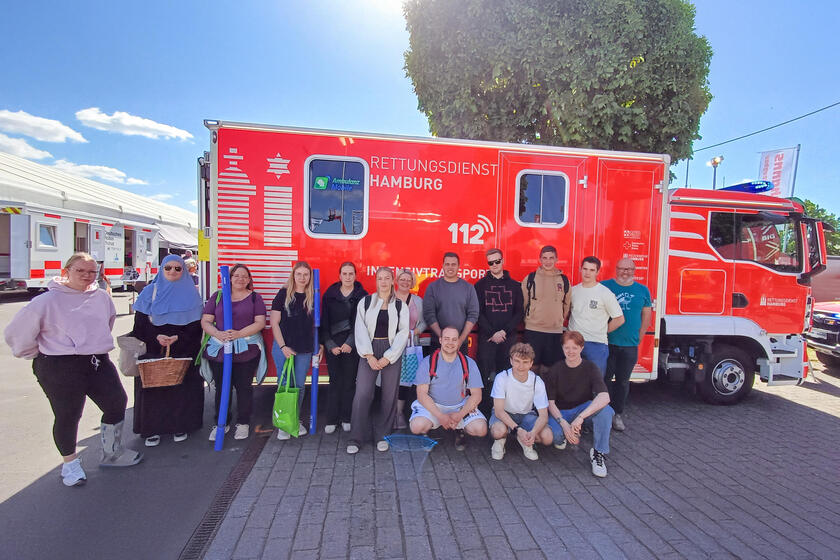 15 Männer und Frauen vor einem Rettungswagen des Rettungsdienstes Hamburg