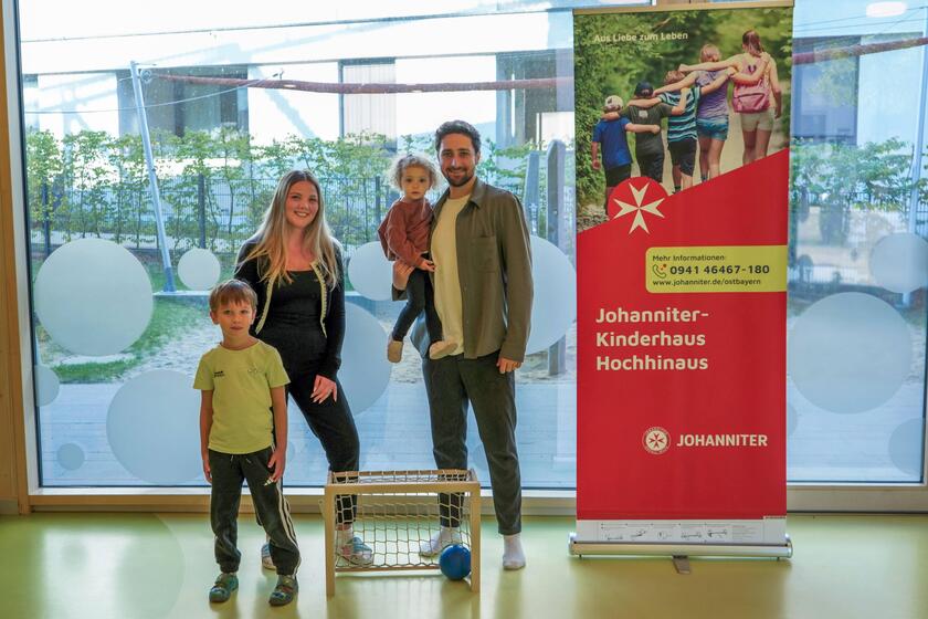 Die Einrichtungsleitung, der Vater und zwei Kinder stehen stolz vor dem Fußballtor