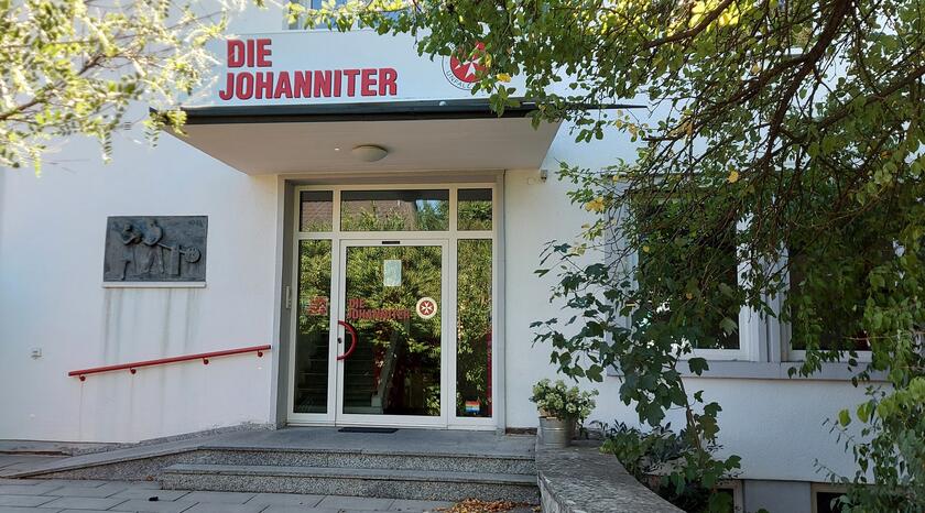 Das Bild zeigt den Eingangsbereich der Johanniter-Dienststelle in Schwabach. Auf dem Vordach ist das Logo zu sehen. Davor steht ein Baum.