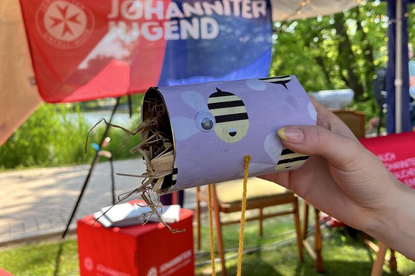 Eine Hand zeigt ein gebasteltes Insektenhotel am Stand der Johanniter Jugend